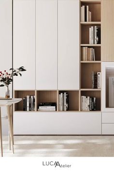 a living room filled with furniture and bookshelves next to a white table topped with flowers