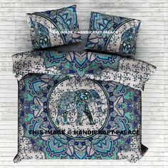 a blue and white comforter set with an elephant in the center on a brick wall