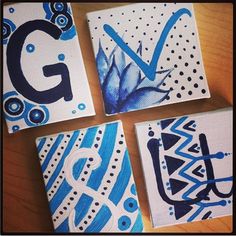 four blue and white paintings sitting on top of a wooden table