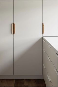 a white cabinet with wooden handles in a room