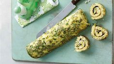 a green cutting board with rolls and a knife next to some napkins on it