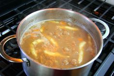 a pot filled with soup sitting on top of an open stove burner next to the oven