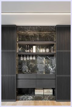 a room with black and white marble walls, wooden flooring and shelves filled with glassware