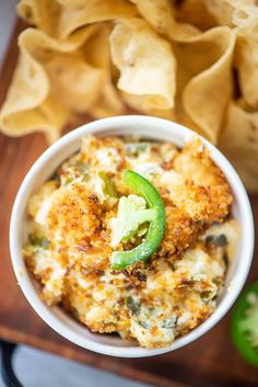 a white bowl filled with food next to tortilla chips