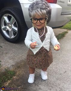 an older woman wearing glasses and holding something in her hand while standing next to a car