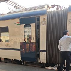 a man standing on the side of a train next to it's loading area