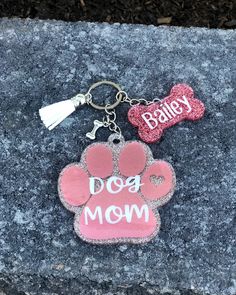 a dog keychain with a pink paw print on it and a bone charm