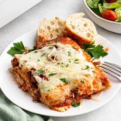 a white plate topped with lasagna and bread