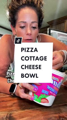 a woman sitting at a table with a sign in front of her that says pizza cottage cheese bowl