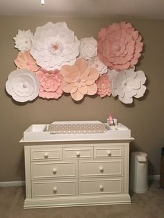 a baby crib in front of a wall with flowers on it and an infant changing table