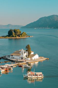 several boats are docked in the water next to a small white house on an island