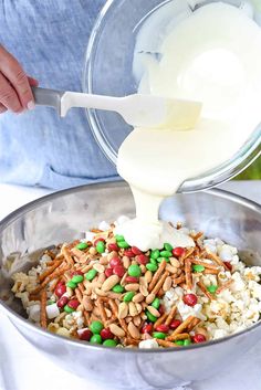 someone pouring milk into a bowl filled with rice and candy caned candies on top