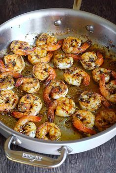 a pan filled with cooked shrimp on top of a wooden table