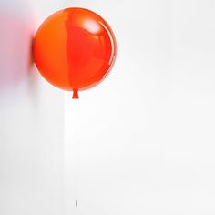 an orange balloon hanging from a white wall