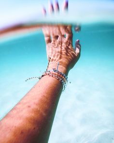 a person's hand is shown in the water with their bracelets on it