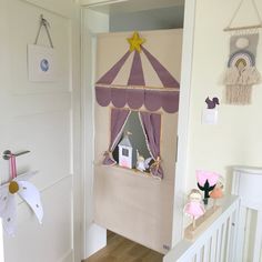 a baby's room decorated in pink and purple with a toy carousel on the wall