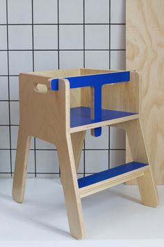 a wooden step stool sitting next to a tiled wall