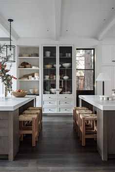 a kitchen with lots of white cabinets and wooden flooring, along with an island in the center