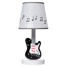 a lamp that has a guitar on it with musical notes in the background and a white shade