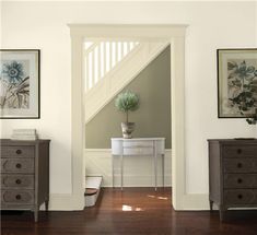 an entry way with two dressers and a potted plant on the table next to it