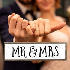 a bride and groom are holding up their wedding sign that says mr & mrs on it