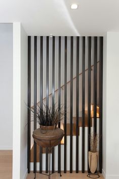 a plant is sitting on a table in front of a wall with vertical slats