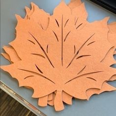 an orange paper cut out to look like a leaf with leaves on the top and bottom