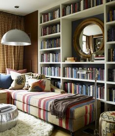 a living room filled with lots of books on top of a book shelf next to a window