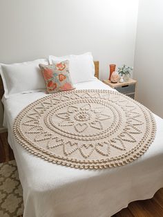 a crocheted bedspread on top of a bed in a room with hardwood floors