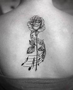 a woman's back with music notes and a rose tattoo