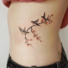 a woman's stomach with two birds on it and some flowers in the back