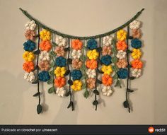 a crocheted wall hanging with flowers and leaves attached to it's sides