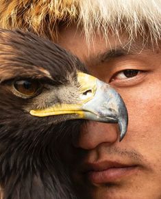 a man is holding an eagle in his hand and it's face close to the camera