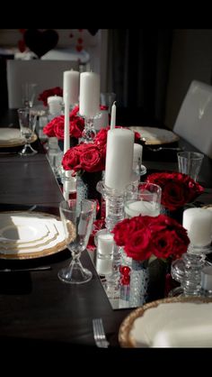 the table is set with candles and red roses