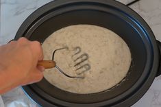 a person using a whisk to stir batter in a crock pot