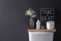 a white toilet sitting in a bathroom next to a chalkboard with the words take a seat on it