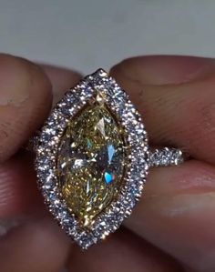 a fancy yellow diamond ring is being held by someone's hand in front of the camera