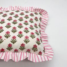 a pink and white striped pillow with flower print on it's ruffled edge