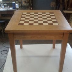 a wooden table with a chess board on it's surface in a workshop area