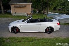 a white bmw convertible parked in front of a house