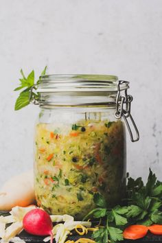 a jar filled with food sitting on top of a table next to carrots and radishes