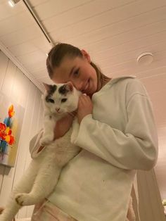 a woman holding a white cat in her arms