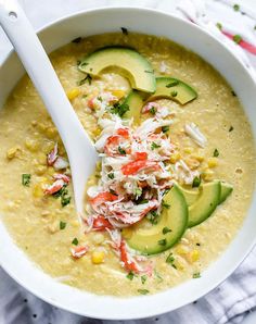 a white bowl filled with soup and topped with avocado