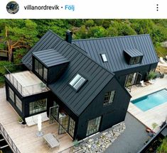 an aerial view of a black house with a pool in the yard and deck area