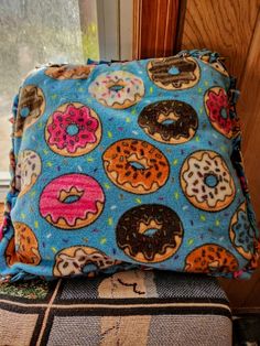 a blue pillow with donuts on it sitting next to a wooden window sill