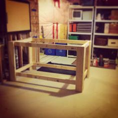 a table made out of plywood in a room filled with shelves and other items