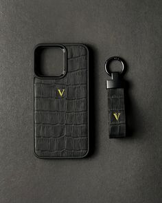 a cell phone case and keychain on a black surface with a gold v logo