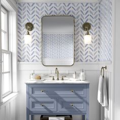 a bathroom with blue vanity, mirror and wallpaper on the walls in shades of blue