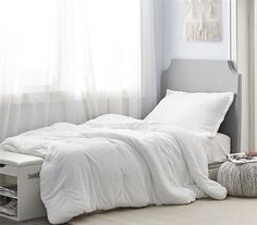 a white bed sitting next to a window in a bedroom