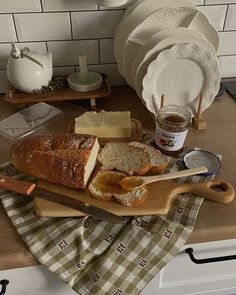 a loaf of bread sitting on top of a cutting board next to plates and butter